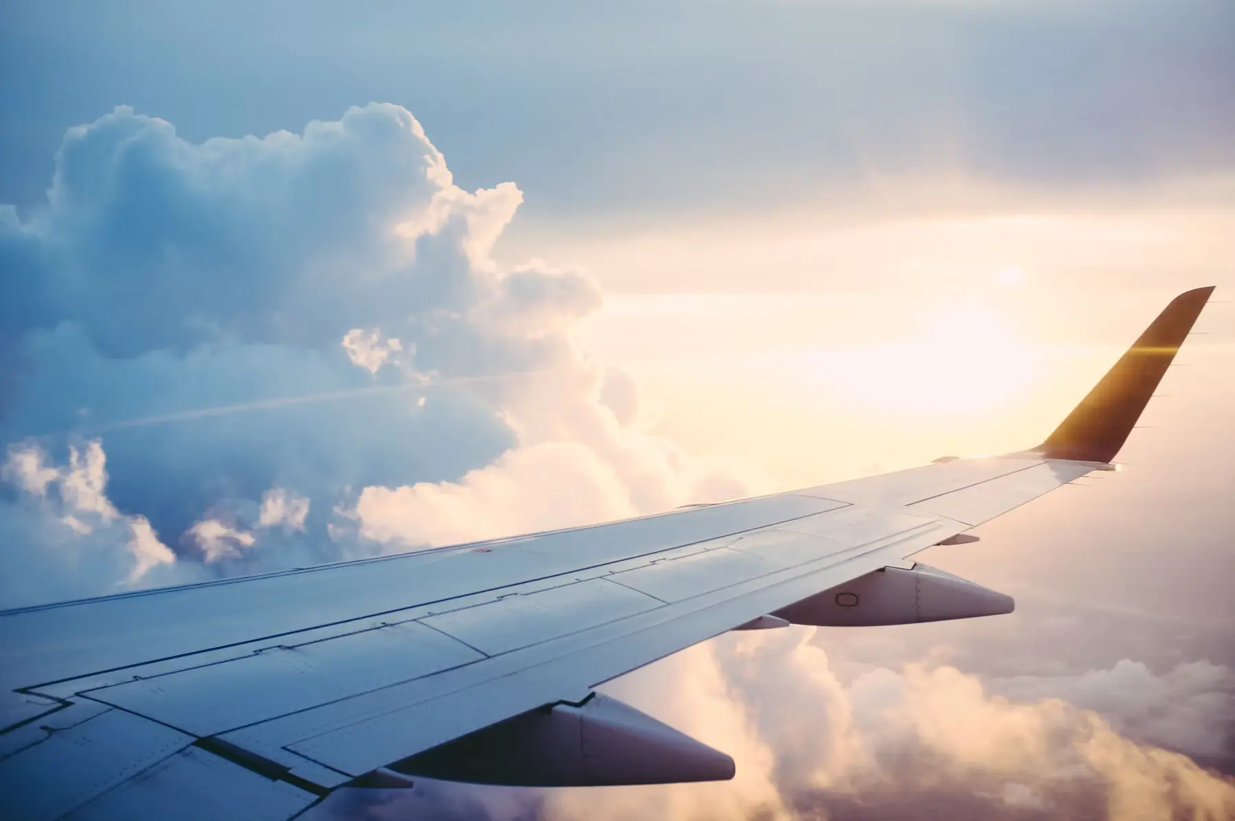 Airplane wing over clouds at golden hour